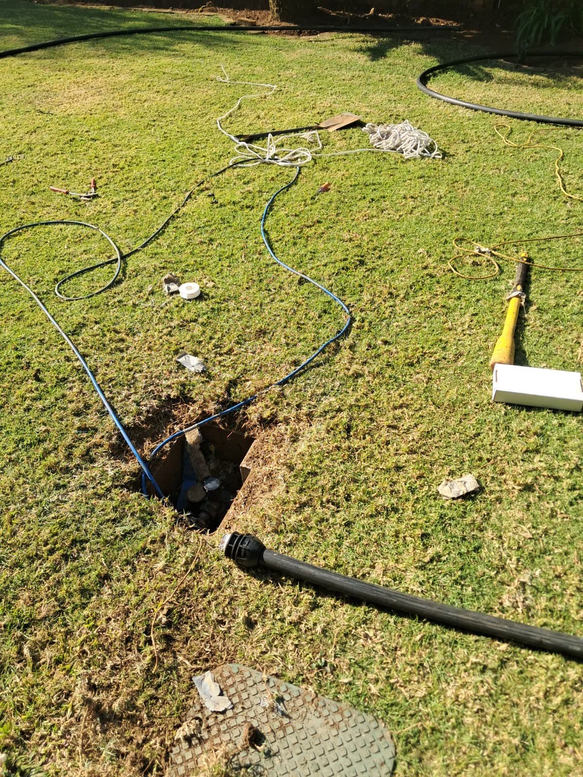 Trenching and pipe reticulation work across a lawn with a valve chamber